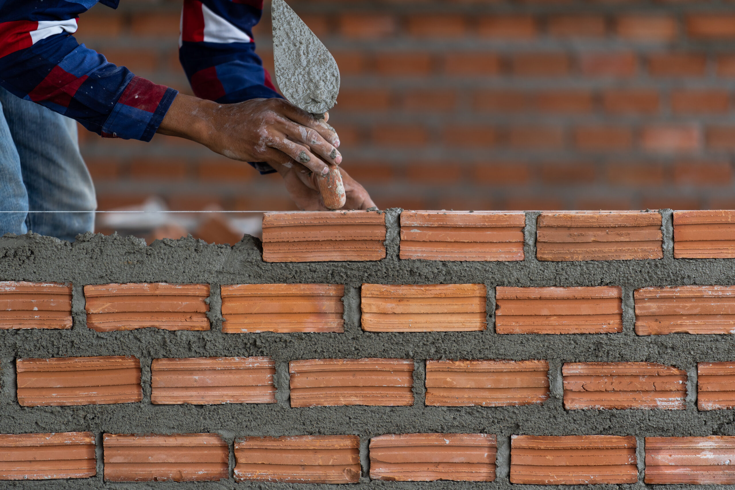 Home closeup hand professional construction worker laying bricks in n